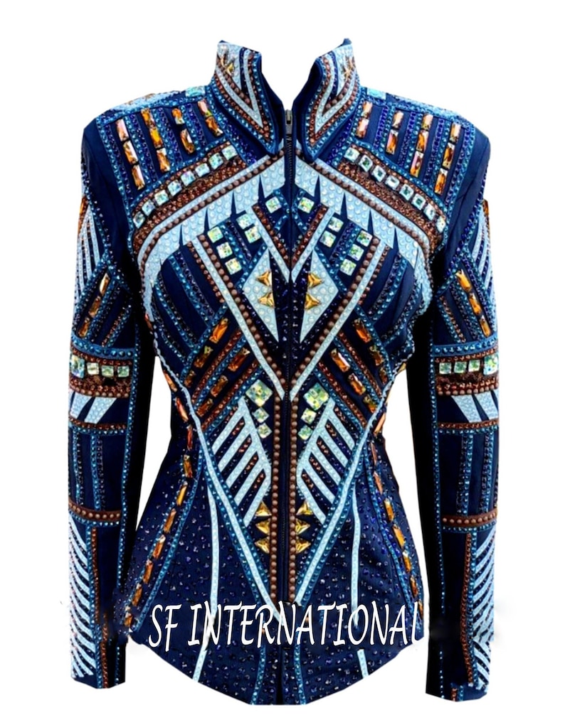 Peut inclure: Une veste de spectacle bleu marine avec un motif g&eacute;om&eacute;trique orn&eacute; d'accents blancs, bleu clair et cuivre. La veste a une fermeture &eacute;clair et est orn&eacute;e de strass. Le texte "SF INTERNATIONAL" est imprim&eacute; en bas de la veste.