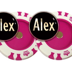 May include: Two pink and white casino chips with a gold "Alex" on a black background. The chips have a white crown design.