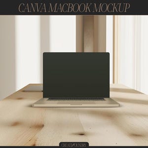 May include: A silver laptop computer with a black screen is sitting on a light brown wooden table. The laptop is open and the keyboard is visible. The table is in a room with a window in the background.