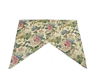 Könnte beinhalten: Eine florale Stoff-Gardinenspitze mit dreieckiger Form. Der Stoff hat einen cremefarbenen Hintergrund mit rosa, blauen und grünen Blumendesigns.