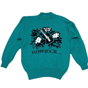 May include: Teal-colored sweater with a mock neck and long sleeves. The front features a black and white floral and guitar design, with the word "ROMANCE..." below the graphic. The sweater is made of a knitted material.