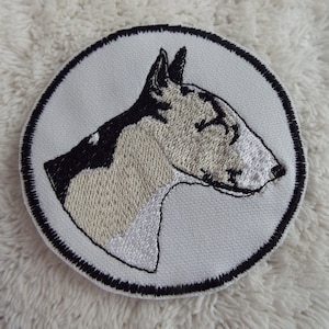 May include: White embroidered patch with a black outline, featuring a white and black bull terrier dog head.