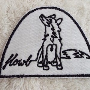 Könnte beinhalten: Weißer gestickter Aufnäher mit schwarzem Umriss. Der Aufnäher zeigt eine Schwarzweiß-Zeichnung eines Wolfes, der zum Mond heult. Der Text "Howl" ist in Schwarz unter dem Wolf gestickt.