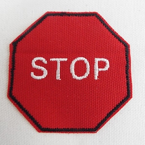 Op de afbeelding: Rood achthoekig stopbord met witte geborduurde tekst "STOP".