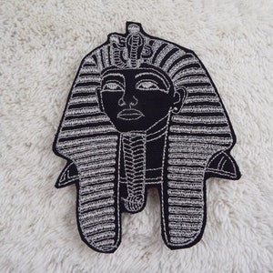 Könnte beinhalten: Schwarz-weiß gestickter Bügel-Patch mit dem Kopf eines ägyptischen Pharaos, der eine traditionelle Kopfbedeckung trägt.