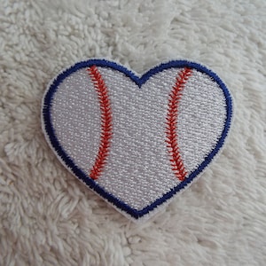 May include: White heart-shaped patch with a red baseball stitch design and a blue outline.