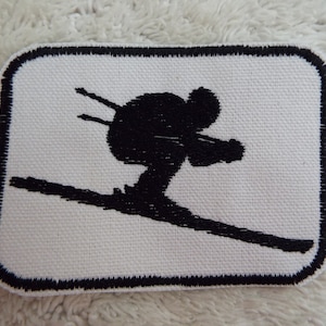 May include: Black and white embroidered patch of a skier in silhouette, with a black border.