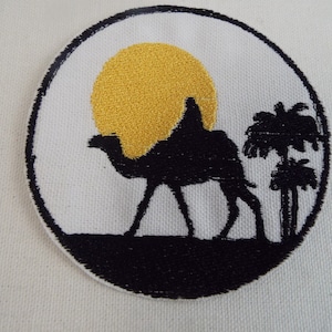 May include: A black and gold embroidered patch featuring a camel silhouette walking across a desert landscape with a palm tree and a yellow sun in the background.