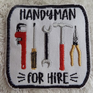 May include: White embroidered patch with black border. The patch features the text "HANDYMAN FOR HIRE" and five tools: a wrench, a hammer, a screwdriver, pliers, and a pipe wrench.