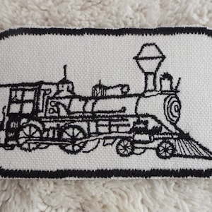 May include: Black and white embroidered patch of a vintage steam locomotive train on a white canvas background with a black border.