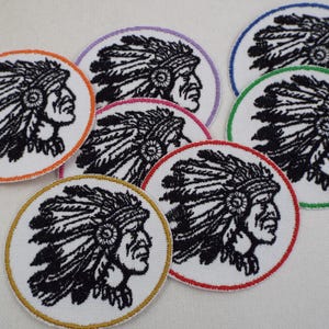 Puede incluir: Un conjunto de diez parches bordados para planchar que representan a un jefe nativo americano con un tocado. Los parches son circulares y tienen un fondo blanco con bordados negros. Cada parche tiene un borde de color diferente.