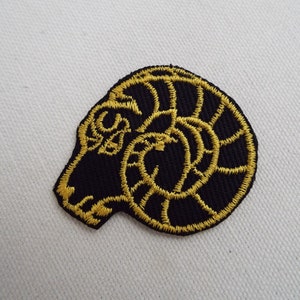 May include: A black embroidered patch with a gold ram's head design.