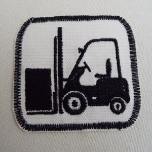 May include: Black and white embroidered patch of a forklift with a square border.