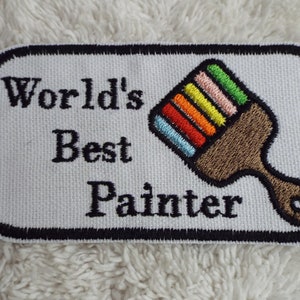 May include: White embroidered patch with black text that reads "World's Best Painter" and a colourful paintbrush design.