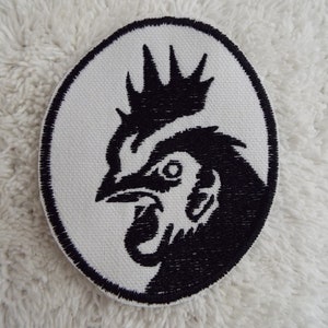 May include: Black and white embroidered patch of a rooster's head in an oval shape.