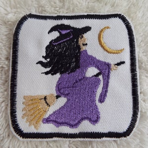 May include: Embroidered iron-on patch featuring a purple witch flying on a broomstick with a gold crescent moon in the background.