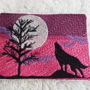 Puede incluir: Parche bordado con la silueta negra de un lobo aullando a la luna, con un árbol en primer plano y un cielo rosa y morado.