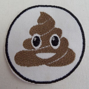 May include: A brown embroidered patch featuring a smiling poop emoji design. The patch is circular and has a black border.