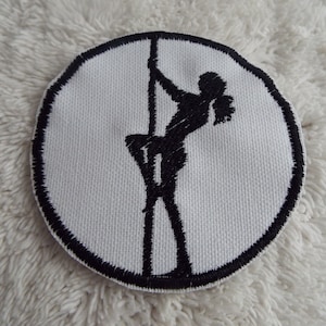 Peut inclure: Un patch circulaire blanc avec une silhouette brodée noire d'une personne sur un poteau.