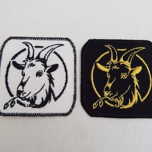 Pode incluir: Dois patches bordados com a cabeça de uma cabra. Um patch é branco com bordado preto, e o outro é preto com bordado dourado.