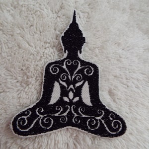 Puede incluir: Parche de hierro negro bordado de un Buda meditando con intrincados diseños florales.