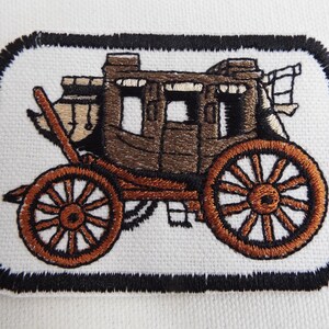 May include: A brown and black embroidered patch of a stagecoach with a black border.