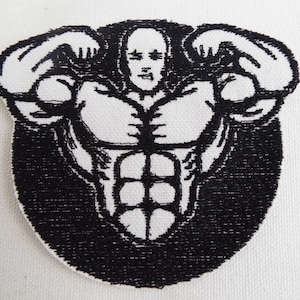 May include: Black and white embroidered patch of a muscular figure flexing both arms. The figure has a defined six-pack and a serious expression.