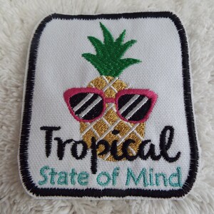 May include: Embroidered iron-on patch with a pineapple wearing pink sunglasses and the text "Tropical State of Mind".
