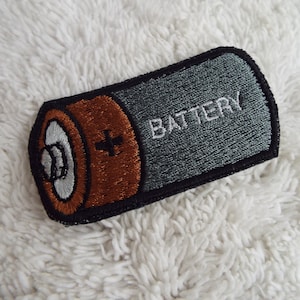 May include: A gray and brown embroidered iron-on patch shaped like a battery with the word "BATTERY" in white text.