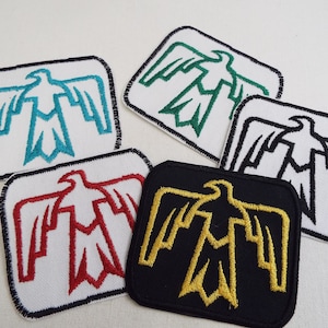 Może przedstawiać: Pięć haftowanych naszywek do prasowania z motywem stylizowanego ptaka. Naszywki są w różnych kolorach, w tym białym, czarnym, czerwonym, zielonym i złotym.