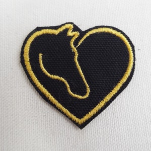 May include: A black heart-shaped patch with a gold outline of a horse's head.