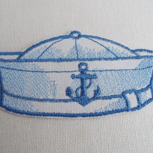 May include: Blue embroidered iron-on patch of a sailor hat with an anchor in the center.
