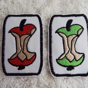 Könnte beinhalten: Zwei Bügelbilder mit einem gestickten Bild eines angebissenen Apfelkerns. Ein Patch hat einen roten Apfel und der andere einen grünen Apfel.