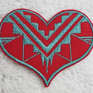 Può includere: Toppa a forma di cuore rossa con un design geometrico turchese. Il design è composto da triangoli e quadrati.