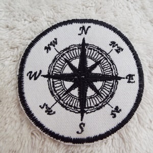 May include: A black and white embroidered compass patch with the directions N, NE, E, SE, S, SW, W, and NW.