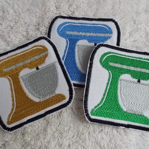 May include: Three embroidered iron-on patches of a stand mixer in blue, gold, and green.