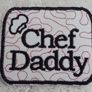 May include: White embroidered patch with a black border and red stitching. The patch features a chef's hat and the text "Chef Daddy".