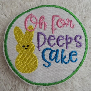 May include: A white embroidered patch with a yellow Peep and the text "Oh for Peep's Sake" in pink, purple, and blue thread.