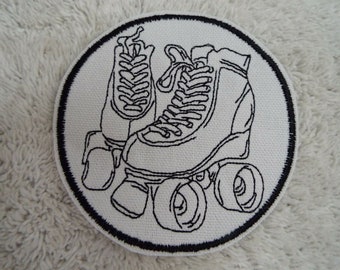May include: Black and white embroidered patch of a pair of roller skates. The skates have laces and wheels.