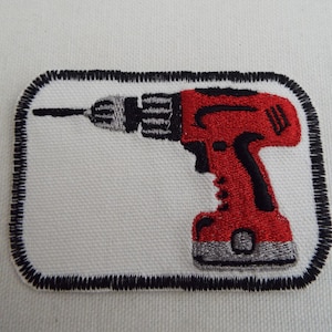 Puede incluir: Parche de hierro bordado en rojo y negro de un taladro sobre un fondo blanco.