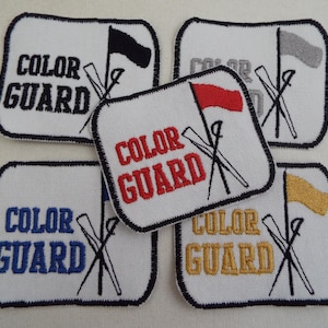 May include: Embroidered patches with the text "COLOR GUARD" in black, red, blue, and gold. Each patch features a flag and crossed ski poles. The flags are black, gray, red, and gold. Patches have a white background and black border.