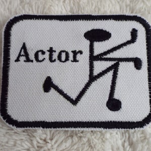 May include: White fabric patch with black embroidered text "Actor" and a stylized symbol.