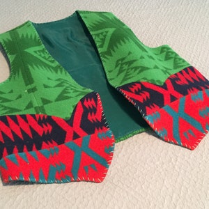 May include: A green, red, blue, and teal patterned vest with a geometric design. The vest is made of a soft, woven fabric and has a lined interior.