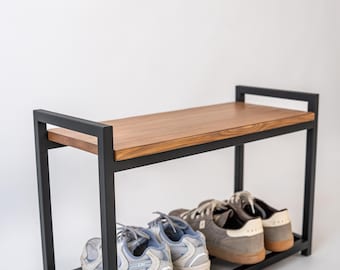 May include: A shoe rack with a black metal frame and a wooden top shelf. The rack has two levels, with shoes on the bottom shelf. The shoes are various colours, including grey and blue.