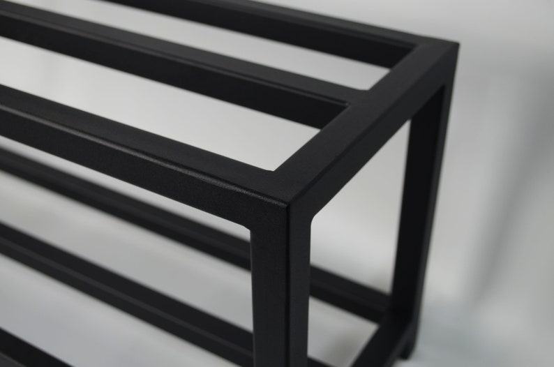 Black metal shelf. The shelf unit is made of square metal tubing and has a simple, modern design.
