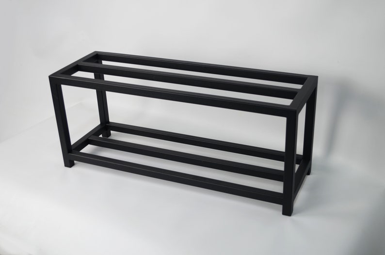 A black metal two tier shoe rack. The shoe rack is made of sturdy metal and has a simple design. It is perfect for storing shoes and keeping them organized.