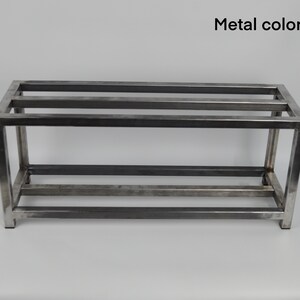May include: A metal shelf unit with three shelves. The shelf is made of square metal tubing and has a clear metal finish.