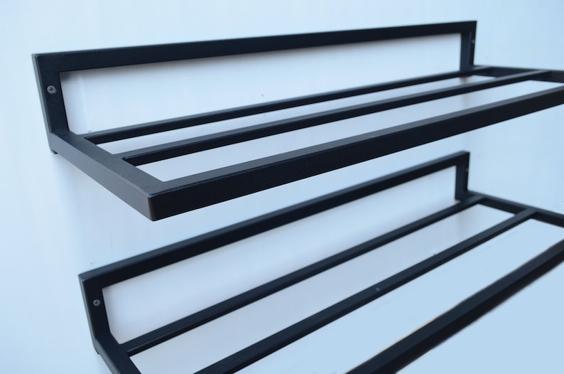 May include: Black metal wall-mounted shoe rack with two shelves. The rack has a simple design with horizontal bars for storing shoes.