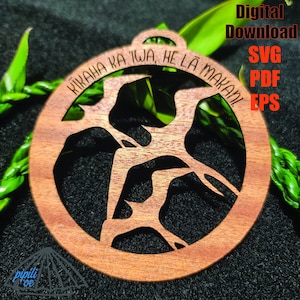 May include: A wooden ornament with a cutout design of a tree branch. The ornament is circular and has the text "KIKAHIA KA 'IWA, HE LA MAKAN" around the edge.