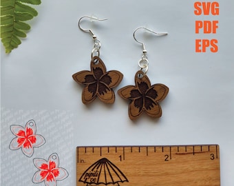 May include: A pair of wooden earrings with a floral design. The earrings are approximately 2.5 cm in diameter and are made of dark brown wood. The earrings are hanging from silver hooks.